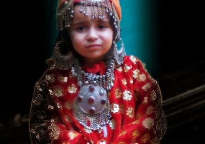 Portrait of smiling girl standing against black background