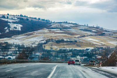 Road by mountain against sky during winter