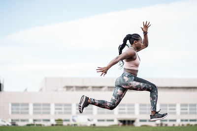 Full length of young woman jumping against built structure