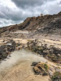 Scenic view of rocky sandy beach against sky