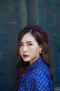 Portrait of young woman standing against metallic gate