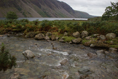 Scenic view of river by mountains against sky