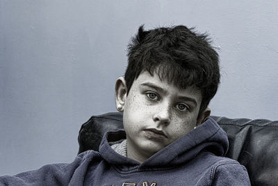 Portrait of young boy standing against wall