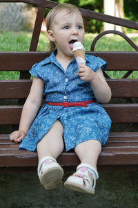 Girl eating ice cream while sitting on park bench