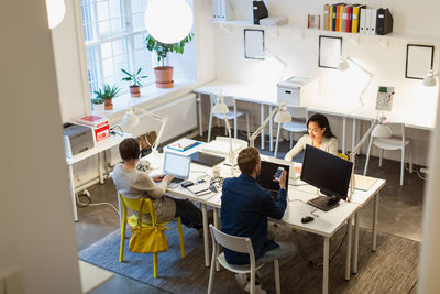 High angle view of multi-ethnic colleagues using technologies at desk in creative office