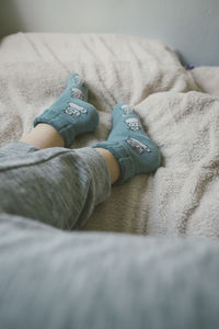 Low section of woman wearing socks resting on bed at home