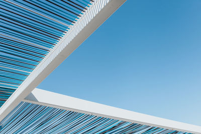 Low angle view of shade structure against clear blue sky