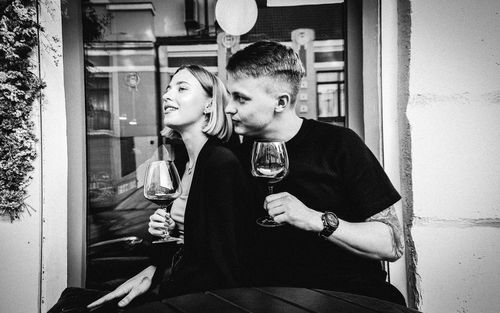 Young couple holding wineglass sitting at restaurant