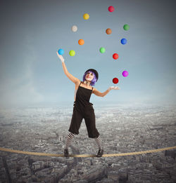 Full length of happy woman with arms outstretched against sky