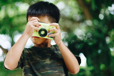 Boy playing with toy camera at park