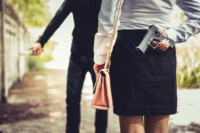 Midsection of man and woman holding weapons while standing on road