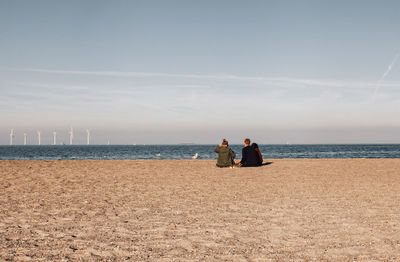 People sitting at beach against sky