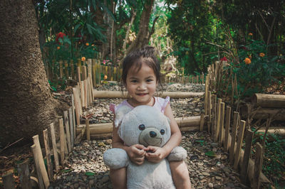 Portrait of smiling girl with toy against trees
