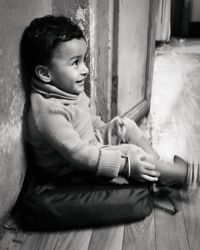 Side view of cute girl sitting on floor at home