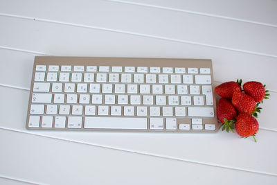 Computer keyboard and strawberries on table