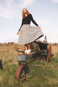 Full length of young woman standing on field against sky