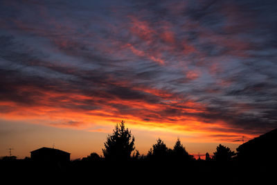 Silhouette trees and buildings against sky during sunset