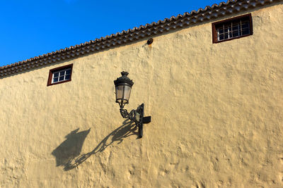 Low angle view of gas slight on building wall during sunny day