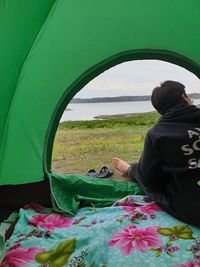 Rear view of teenage boy sitting in tent