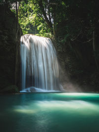 Scenic waterfall smooth stream, sunbeam and turquoise pond. erawan falls, kanchanaburi, thailand.
