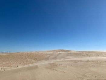 Scenic view of desert against clear blue sky