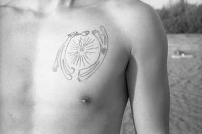 Close-up of shirtless man with tattoo on chest
