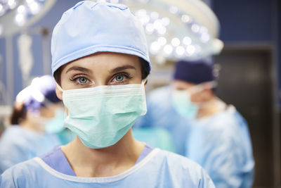 Portrait of female doctor with coworkers in background at operating room