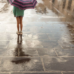 Low section of woman standing on wet street