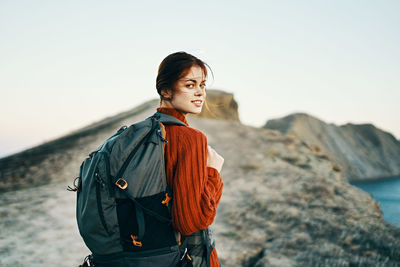 Young woman looking away against clear sky