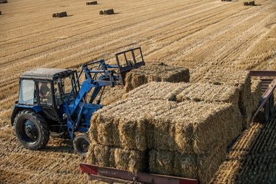 High angle view of tractor with hay bales on field