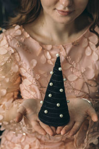 Close up shot of female hands holding small black christmas tree celebrate on christmas holiday pink
