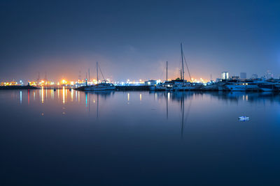 Boats moored at harbor against sky at night
