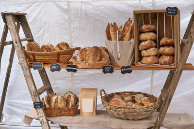 The rustic practical bread display of a baker - fresh loaves arranged in baskets on wooden shelves.