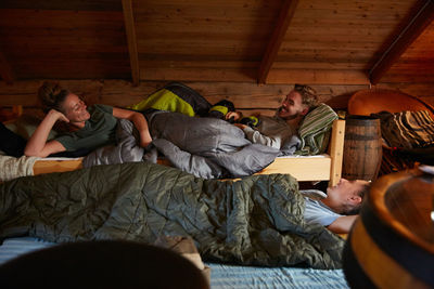 Smiling friends talking while resting in log cabin during bedtime