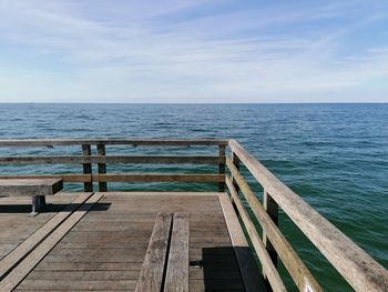 Wooden pier on sea against sky