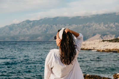 Woman standing in sea against mountains