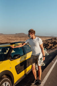 Full length of man standing on road against clear sky