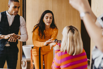 Female entrepreneur applying essential oil sample on colleague's hand during event at convention center