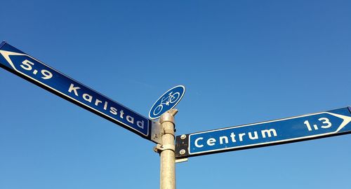 Low angle view of road sign against clear blue sky