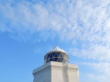 Top of a white lighthouse underneath a clear blue sky