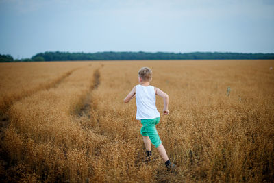 Rear view of boy running on field