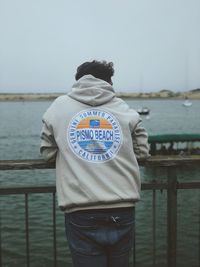 Rear view of man looking at sea against sky