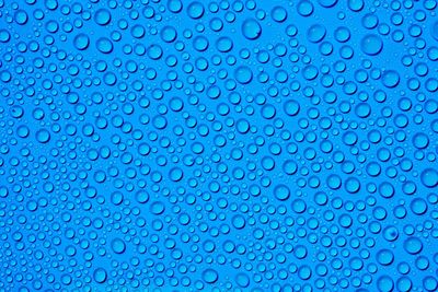 Full frame shot of water drops on blue background