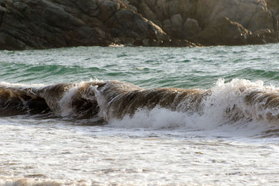 People playing, swimming in the waves in the island of patmos, greece in summer time