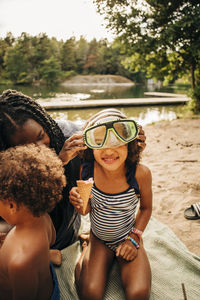Woman helping daughter to wear swimming goggles on vacation