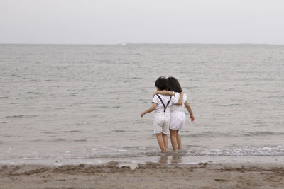 Rear view of man standing at beach against sky