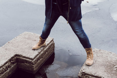 Low section of man standing on retaining wall over river