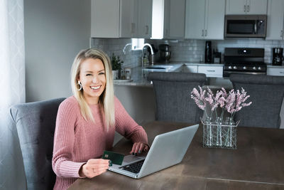 Portrait of smiling young woman using smart phone at home