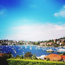 High angle view of townscape by sea against blue sky