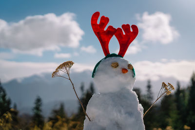 Close-up of a snowman with antlers in mountains 